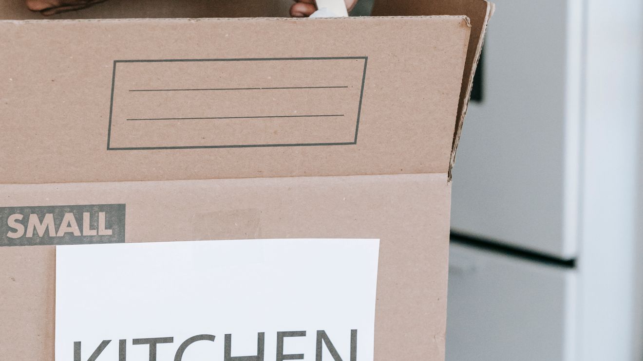Kitchen items being wrapped and placed into a labeled moving box